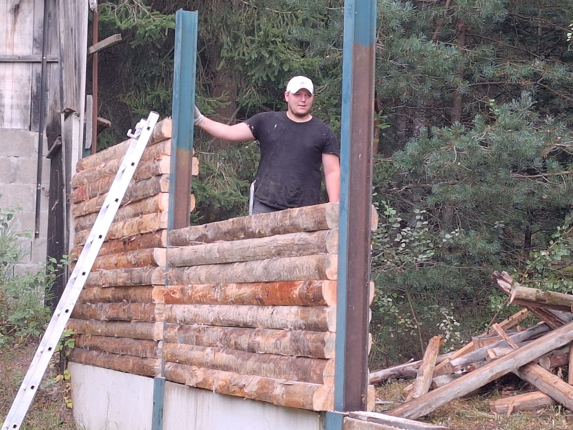 Bénévole posant les premiers rondins du mur du pare-balles 25 m