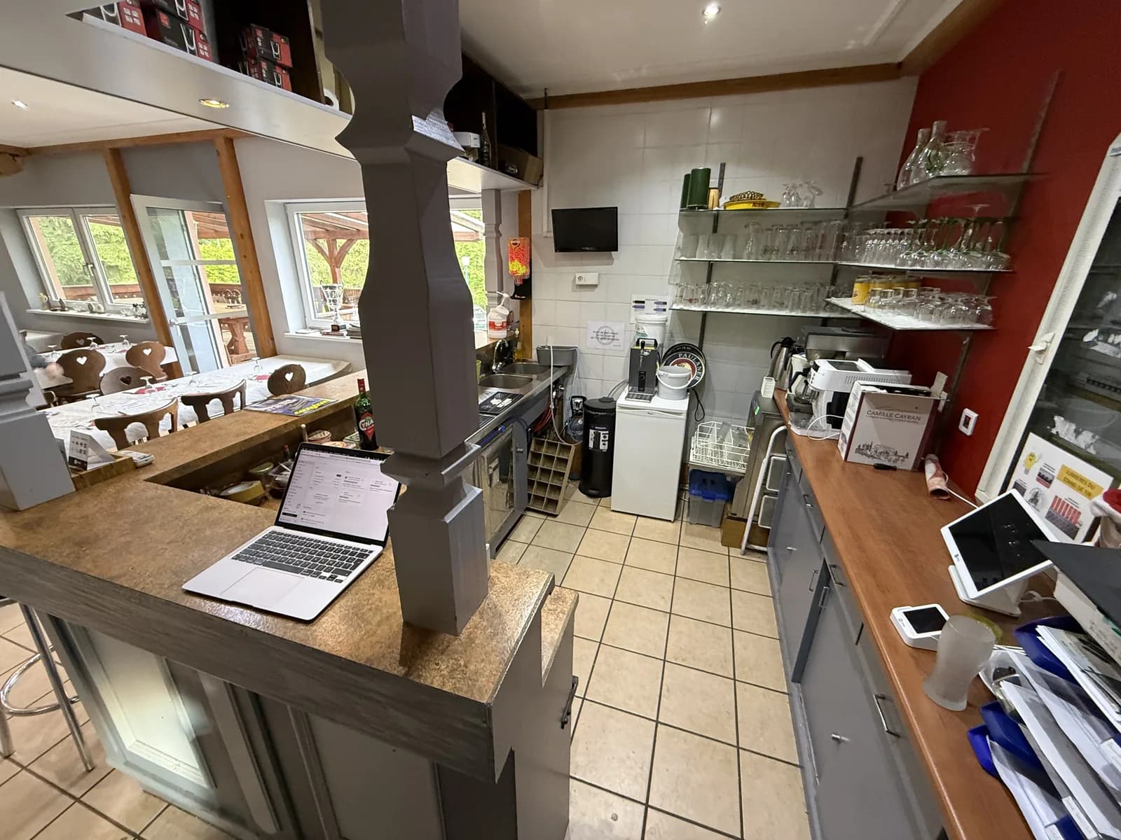 Comptoir du bar avec verres rangés et vue sur la salle