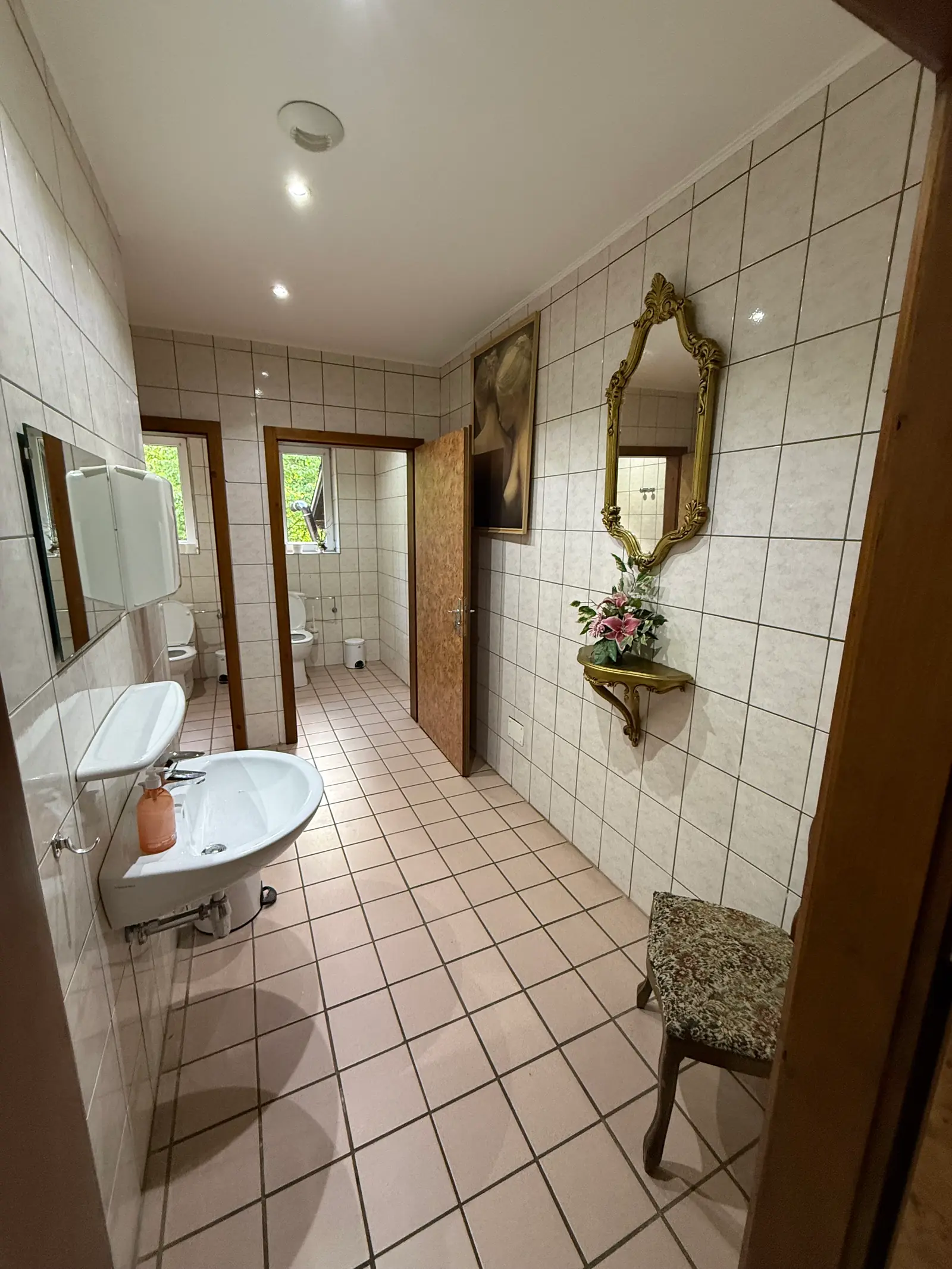 Sanitaires femmes du club : faïence claire, miroir doré, fleurs
