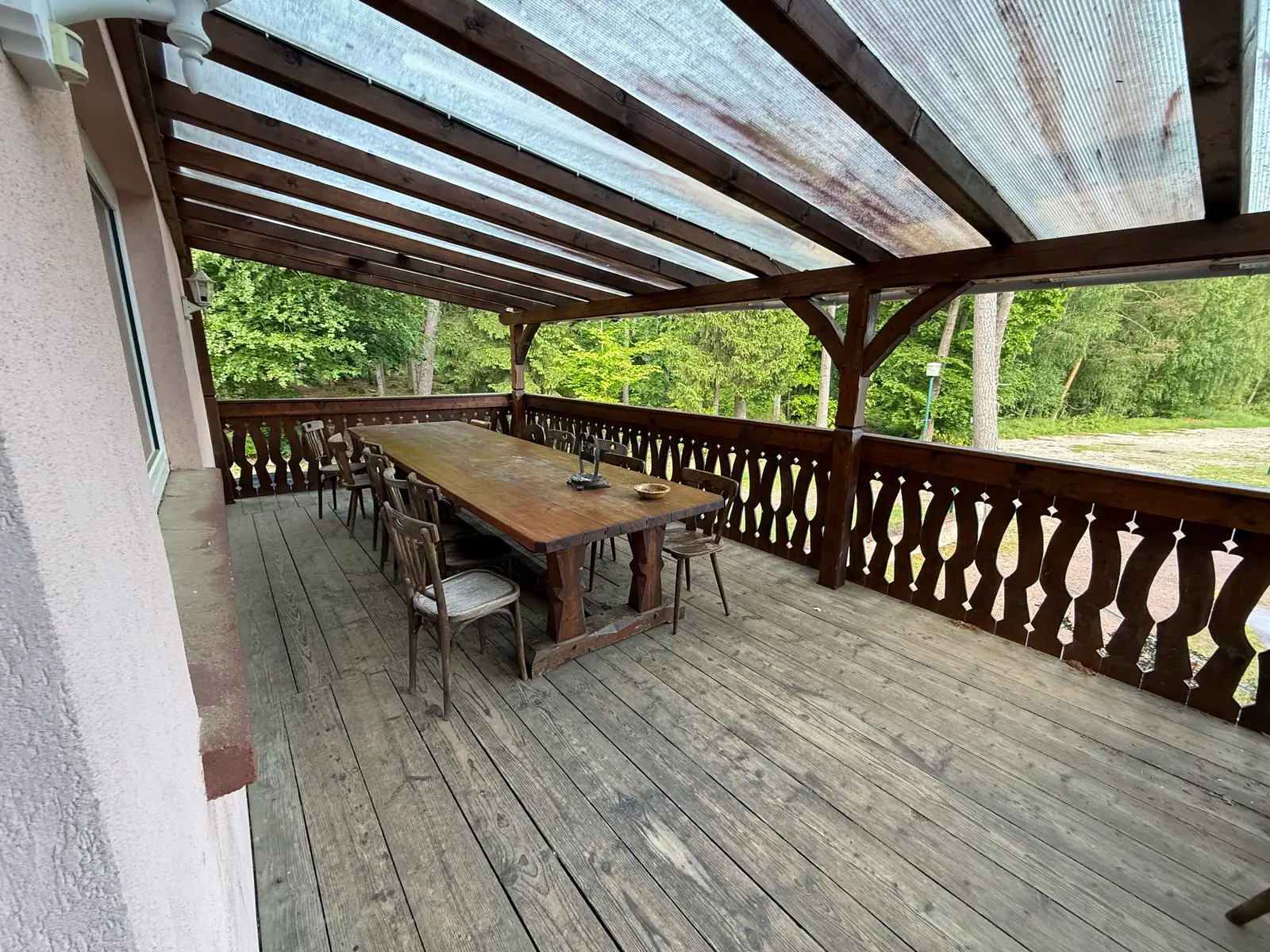 Grande terrasse couverte avec table en bois, charpente alsacienne et vue sur la forêt