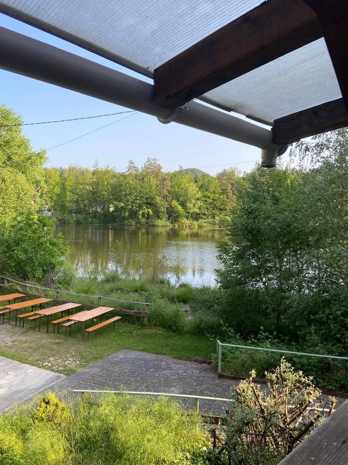 Vue depuis la terrasse couverte sur l'étang en contrebas et les tables de pique-nique