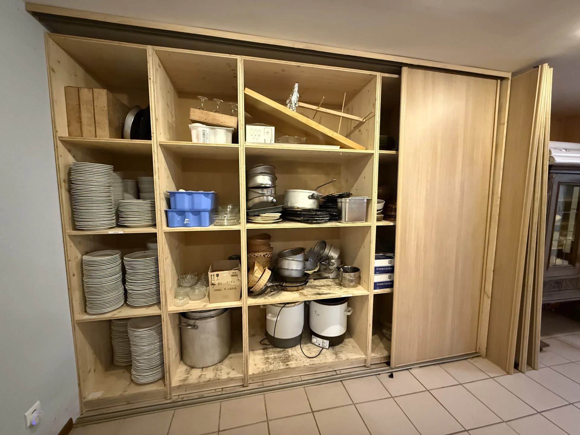 Étagères de rangement avec assiettes empilées, plats, casseroles, marmites et ustensiles de cuisine